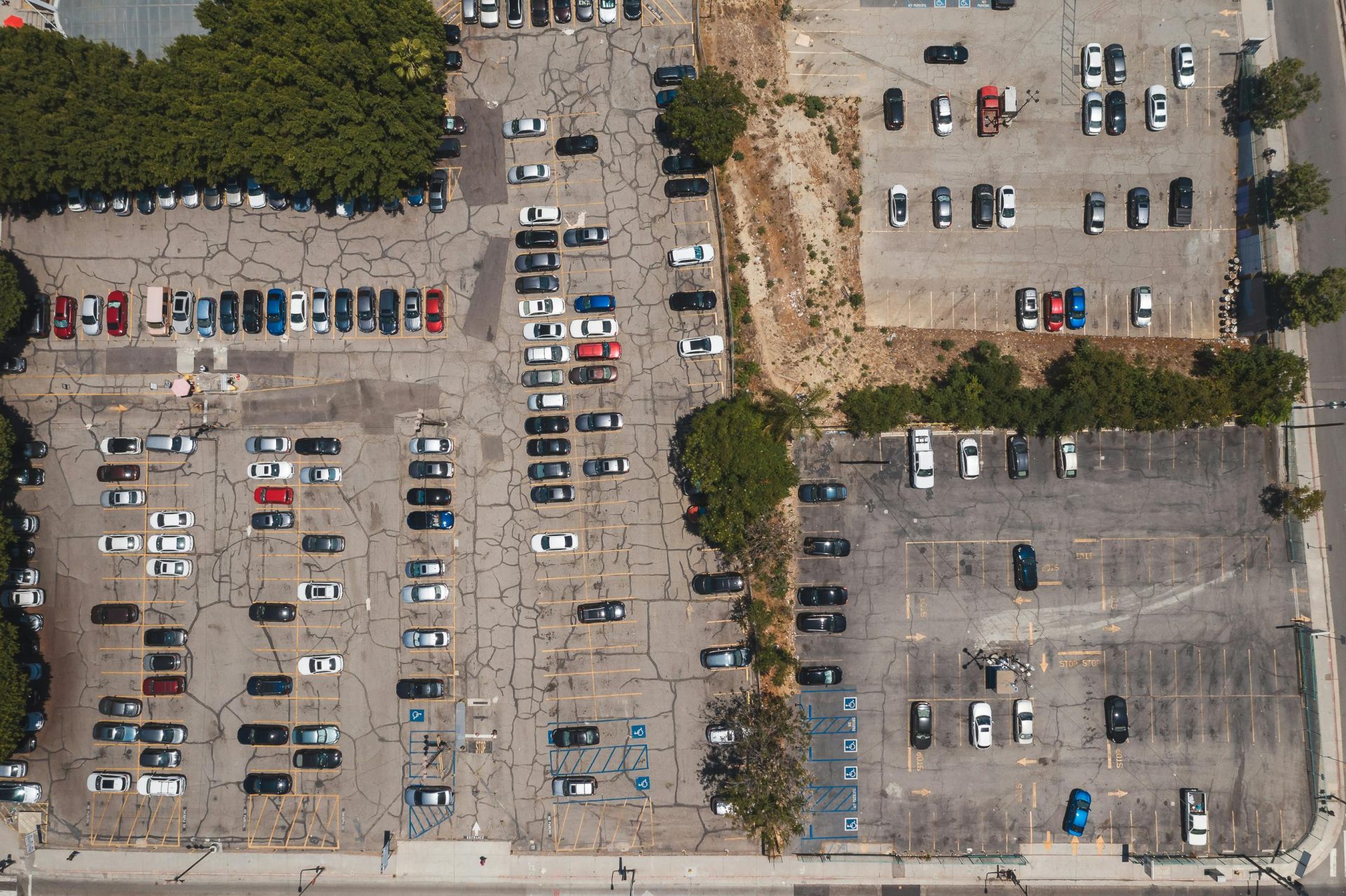 Luftaufnahme eines städtischen Parkplatzes voller geparkter Autos mit einer Drohne, die die städtische Infrastruktur zeigt.